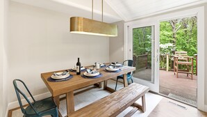 Un comedor con una mesa de madera dispuesta para cuatro personas, un banco y una lámpara colgante.