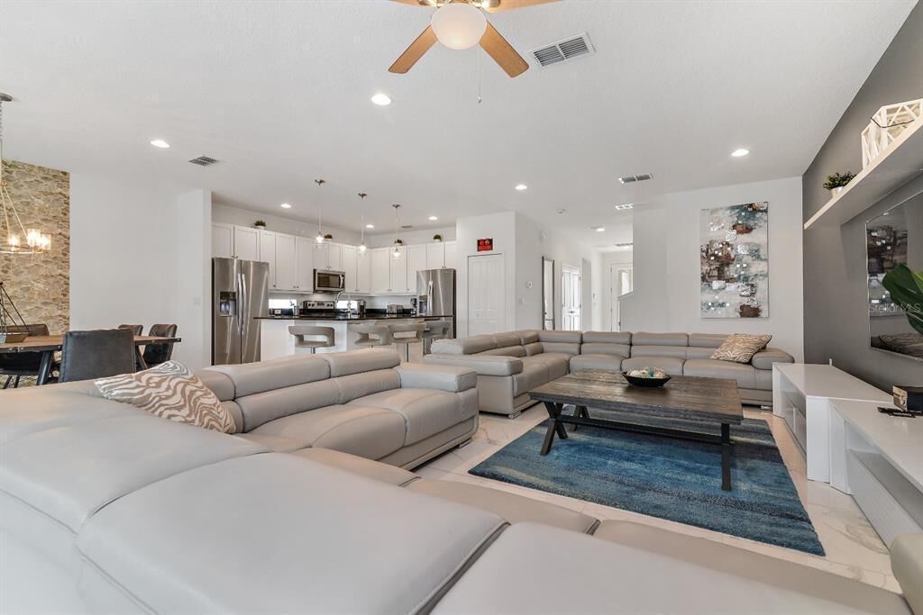 A modern living room with a sectional sofa, a coffee table, and a dining area with a chandelier.