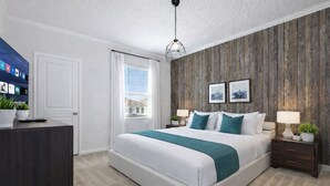 A bedroom with a bed, bedside tables, a desk, a television, and a window with curtains. - Mystical Dreams (Kissimmee)