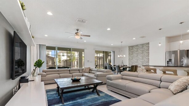 A modern living room with a large sectional sofa, a coffee table, and a TV mounted on the wall. - Mystical Dreams (Kissimmee)