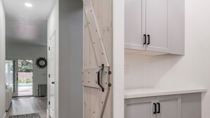 A hallway with a sliding barn-style door, white cabinets, and a patterned rug. - Casa de Panda - 4-bedroom house with heated pool (Sacramento)