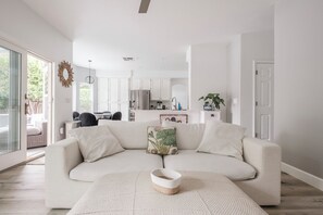 Ein modernes Wohnzimmer mit einer Couch, einem Couchtisch und einer Küche im Hintergrund.