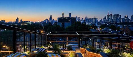 A rooftop terrace with seating areas and a city skyline view.