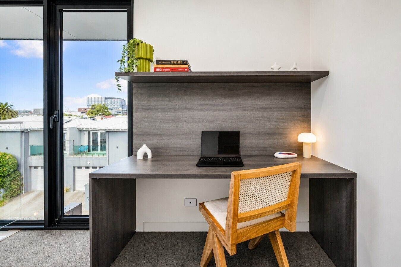 Een moderne werkplek met een laptop, een bureaulamp en een stoel.