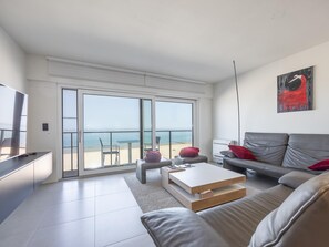 Een moderne woonkamer met een balkon, een bank, een salontafel en een schilderij.
