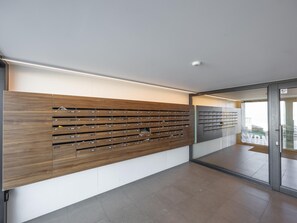 Ein modernes Interieur mit einer wandmontierten Briefschlitzanlage, einer Glastür und einem gefliesten Boden.