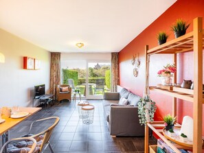 A modern living room with a sofa, dining table, chairs, and a balcony with a view. - Charming apartment close to the the beach (Sint-Idesbald)