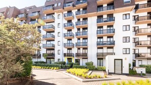 Un immeuble résidentiel à plusieurs étages, doté de balcons, d’une entrée sécurisée et d’espaces paysagers.