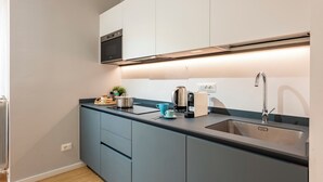 A modern kitchen with a built-in oven, a stainless steel sink, and a coffee maker. - Maison Columbus in the Heart of Genova (Genoa)