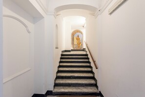 A staircase with a handrail, white walls, and a decorative window at the top.