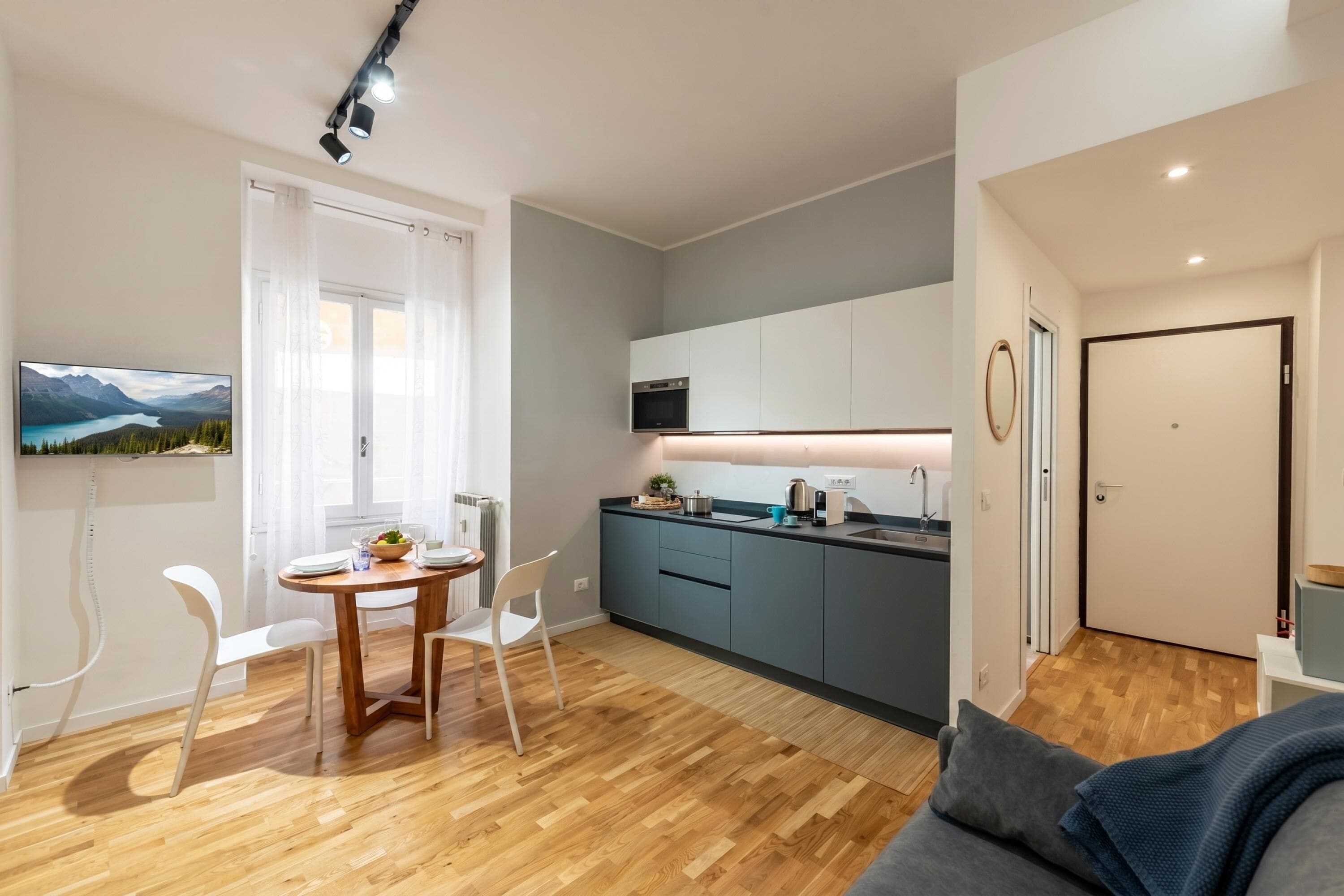 Una cucina moderna con zona pranzo, pavimento in legno e vista sulle montagne attraverso una finestra.
