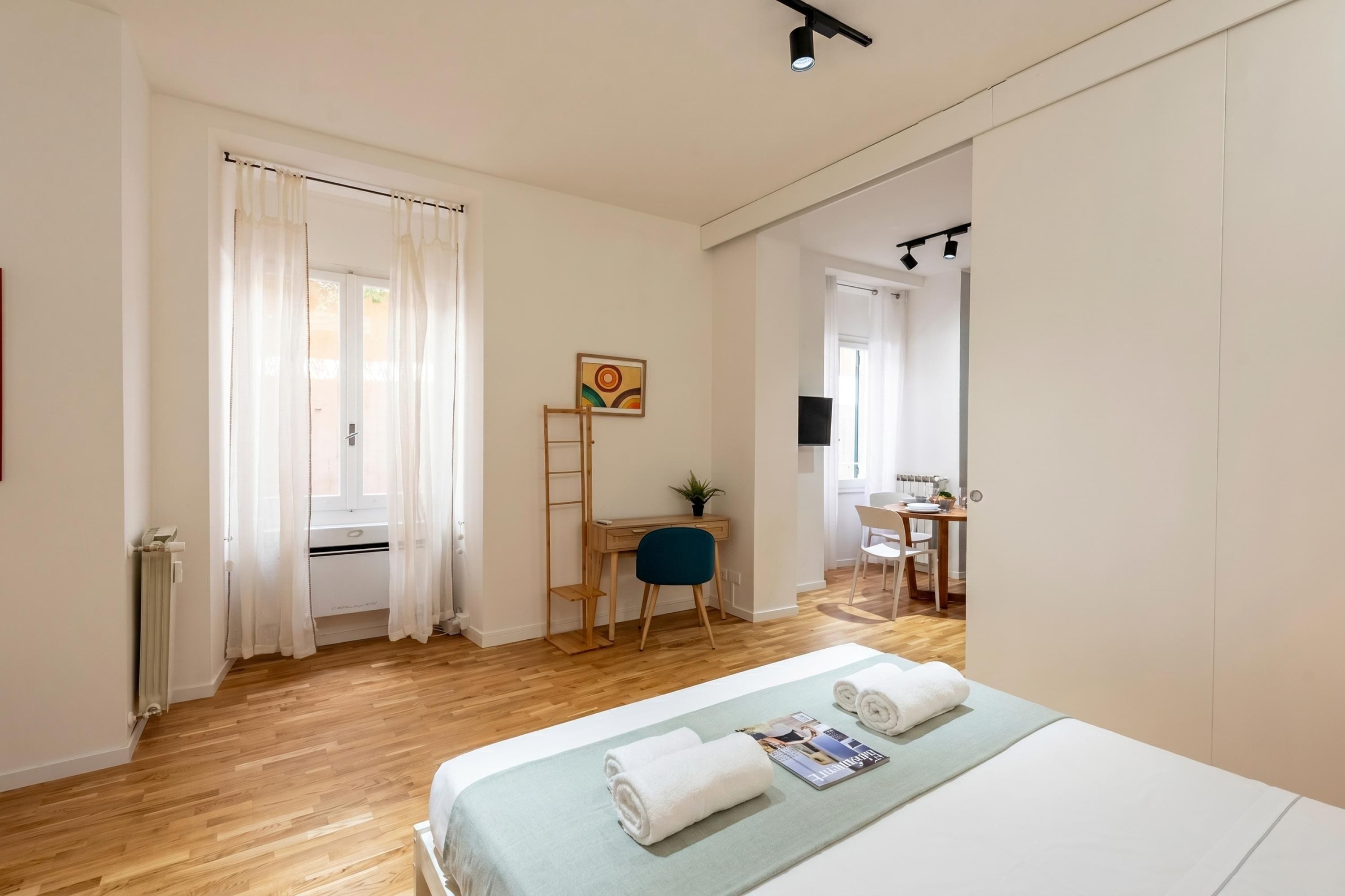 A hotel room with a bed, a desk, a chair, and a TV.