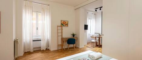 A hotel room with a bed, a desk, a chair, and a TV.
