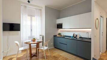 Una cucina compatta con zona pranzo, TV a schermo piatto e design moderno.