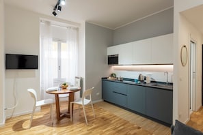 A compact kitchen with a dining area, a flat-screen TV, and a modern design.