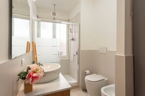 Un baño moderno con un lavamanos grande, inodoro y ducha.