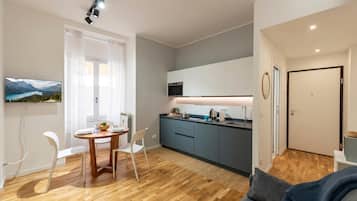 Una cucina moderna con zona pranzo, pavimento in legno e vista sulle montagne attraverso una finestra.