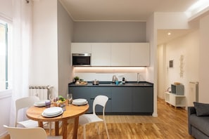 Una cocina moderna con armarios blancos, horno empotrado y una isla central con pileta.