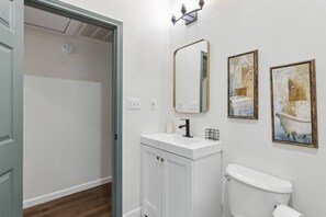 Een badkamer met een toilet, een wastafel en twee spiegels. Twee kunstwerken hangen in de lijst aan de muur.