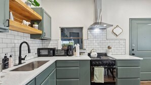 A kitchen with a sink, a stove, a microwave, and a kettle. - Charming, Cozy, Central & Convenient Home (Dallas)