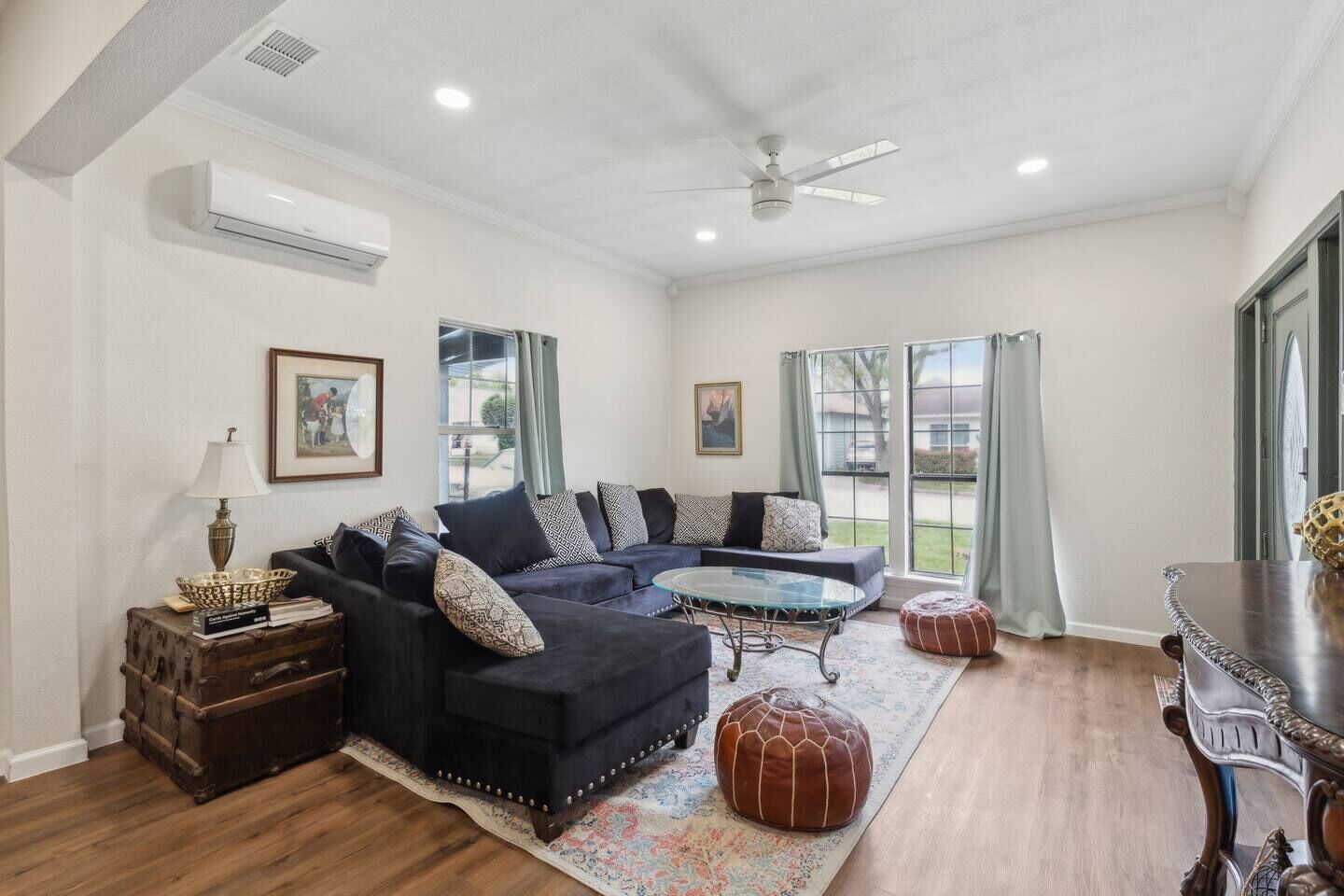 A living room with a sectional sofa, a glass coffee table, a wooden side table, and a decorative lamp.