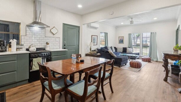 A spacious living area with a dining table, chairs, a sofa, and a kitchen with a stove and cabinets. - Charming, Cozy, Central & Convenient Home (Dallas)