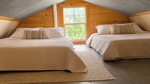 Una camera da letto mansardata accogliente, con due letti, una grande finestra e un soffitto spiovente.