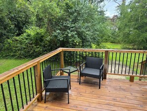 A wooden deck with two wicker chairs and a small table.