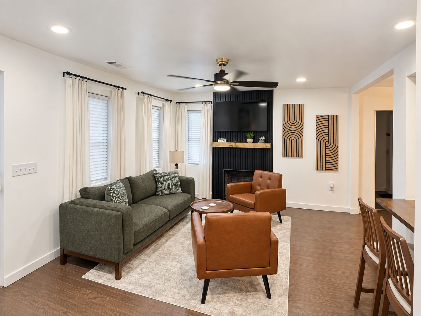 A modern living room with a sofa, armchairs, a coffee table, and a dining area with chairs and a table.
