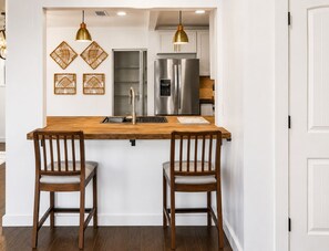 A kitchen with a wooden island, stainless steel appliances, and two bar stools. - In-Town Sylvania Cottage with Fireplace, Deck & Renovated Interior (Sylvania)