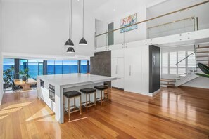 A modern kitchen with a large island, bar stools, and a view of the ocean.