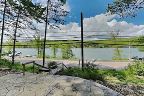 A paved area with a stone pattern, a metal railing, and a view of a lake with a distant shoreline. - Lakeside Ease (Oakland)