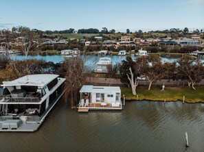 A floating houseboat docked at a marina with a view of the surrounding residential area.
