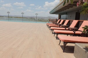 Una terraza con filas de sillones naranja, una vista despejada del cielo y un paisaje distante.