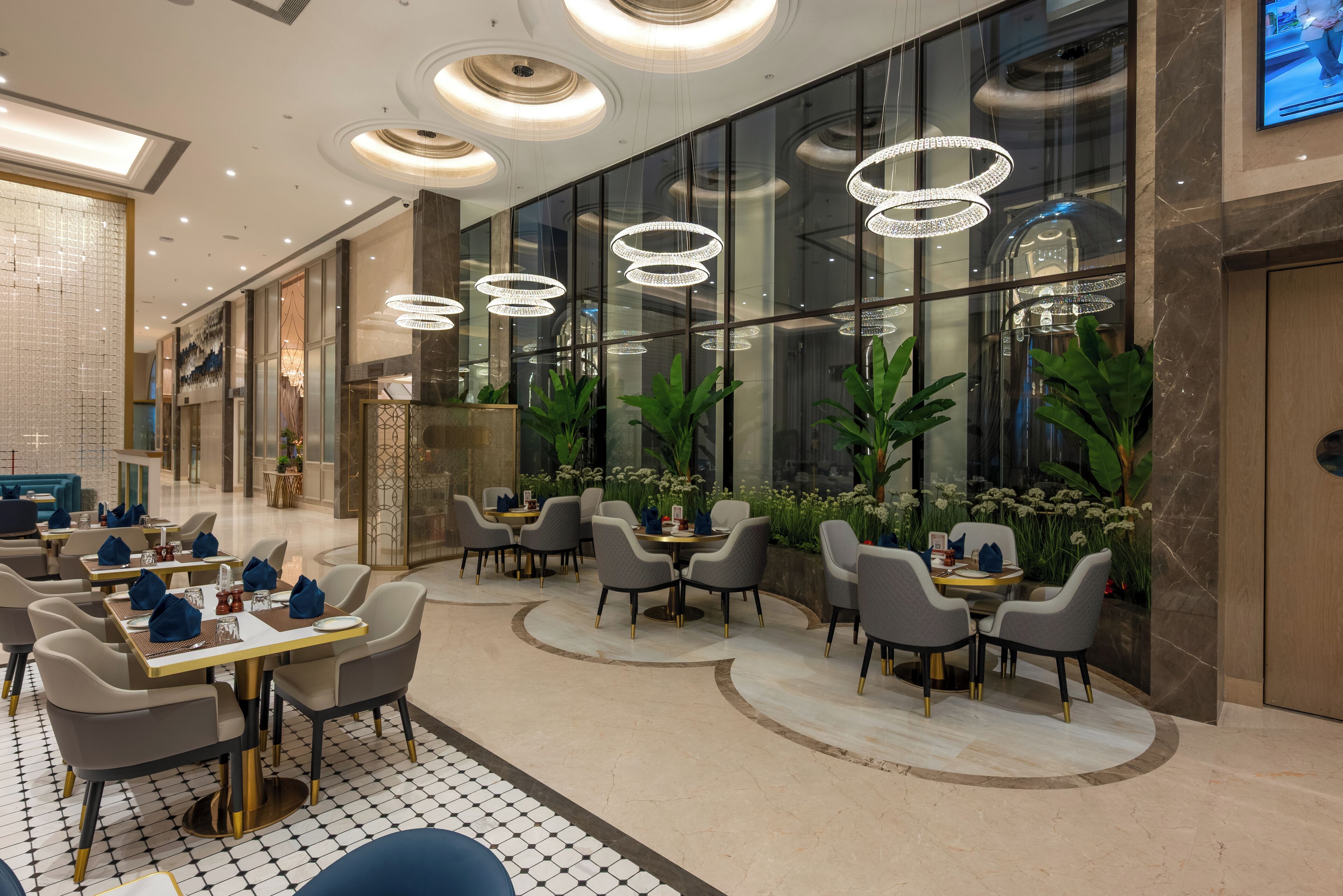 Un lobby de hotel moderno con una zona de estar central, ventanas amplias e iluminación decorativa.