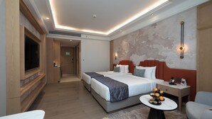 Een hotelkamer met een groot bed, nachtkastjes, een televisie en een eethoekje.