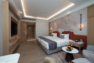 A hotel room with a large bed, bedside tables, a TV, and a small dining area.