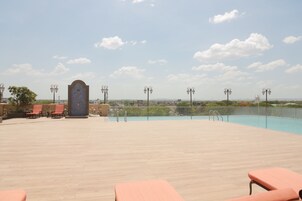 Un área de piscina en la azotea con sillones, vistas a la ciudad y un arco decorativo.
