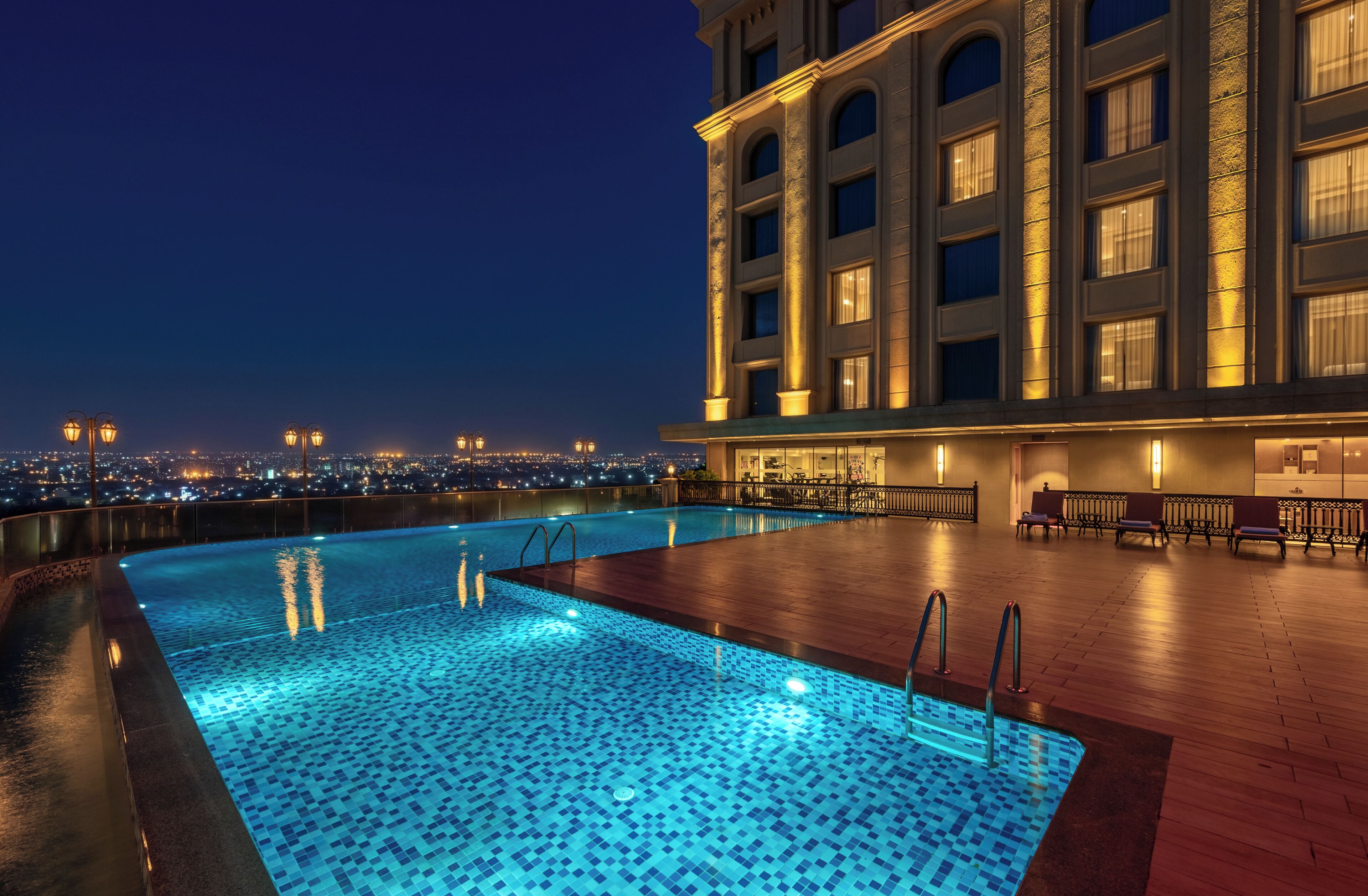 A rooftop pool with a city view, a bar area, and a building with classical architecture.
