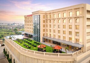 A hotel with a large glass facade, multiple balconies, and a landscaped terrace. - Hotel Express Inn Heritage (Chhatrapati Sambhajinagar)