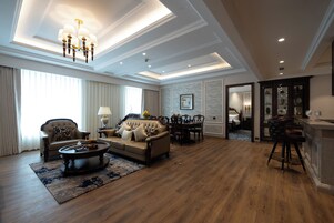 A spacious living room with a large sofa, a coffee table, and a dining area with chairs.