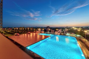 Una piscina con vista a un paisaje urbano al anochecer.