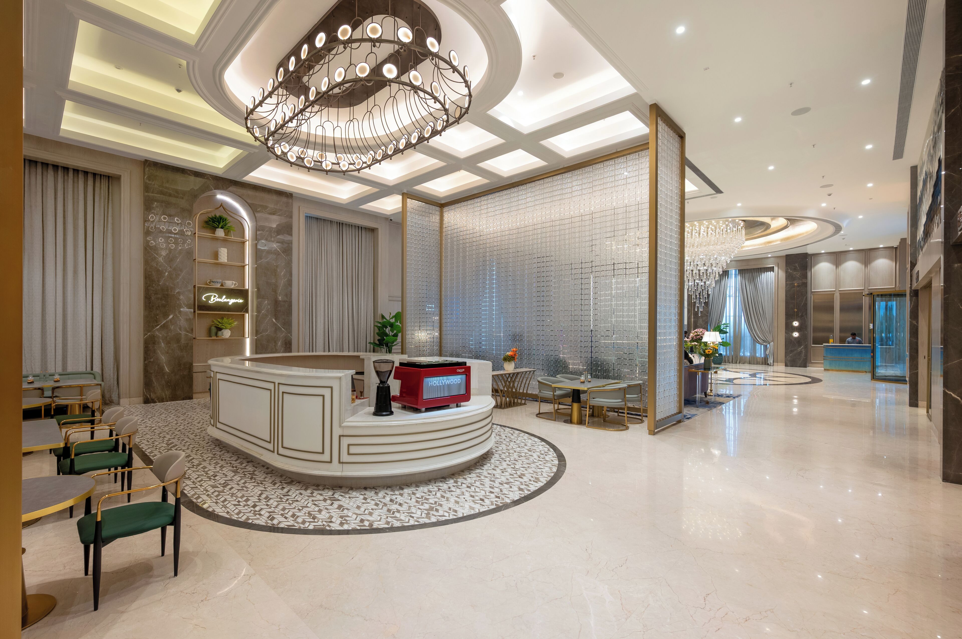 A modern hotel lobby with a reception desk, seating area, and a decorative chandelier.