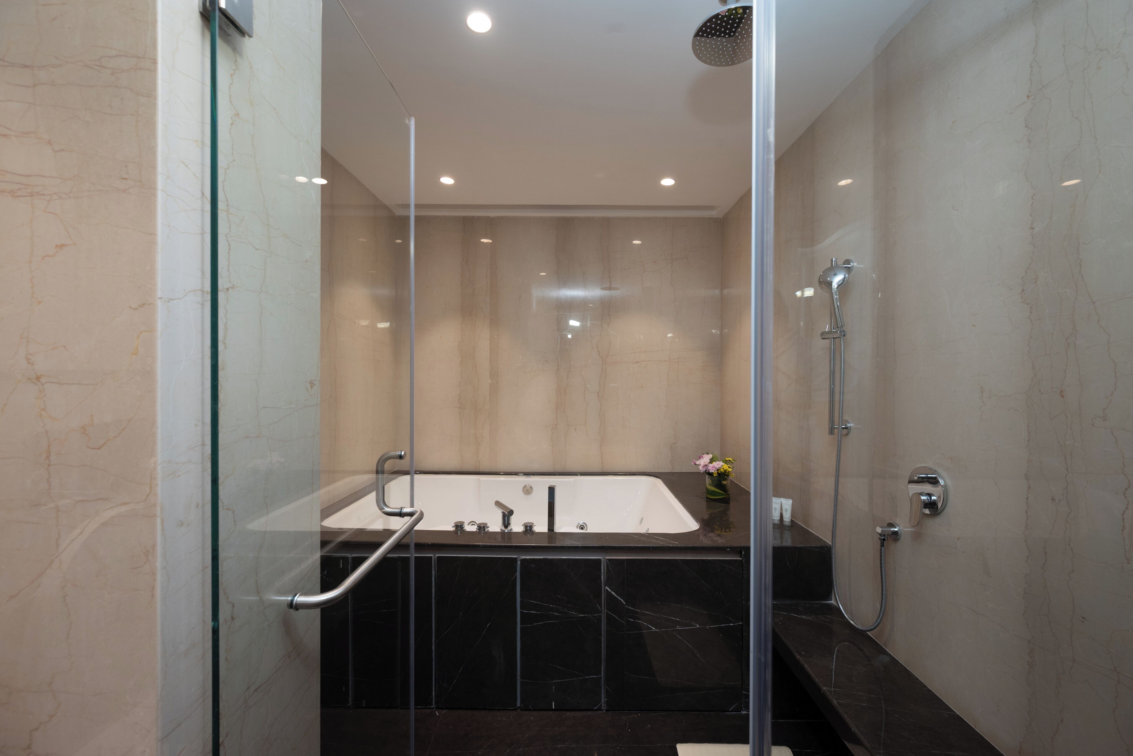A modern bathroom with a glass-enclosed shower, a freestanding bathtub, and a marble-tiled floor.