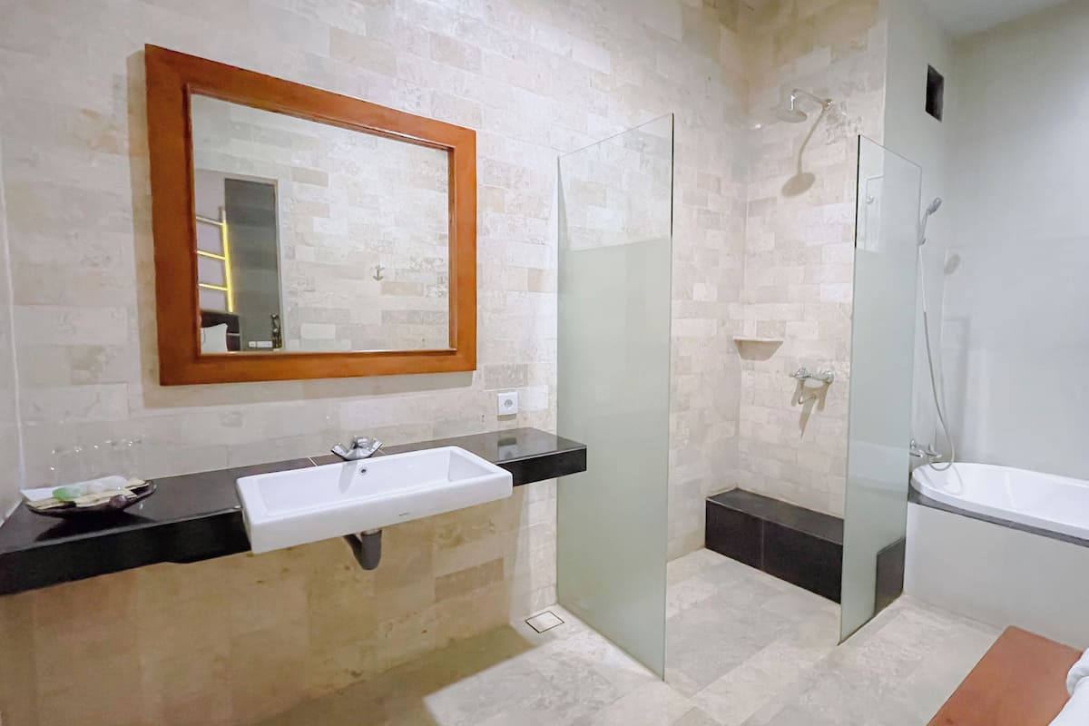 A bathroom with a sink, mirror, shower, and bathtub.