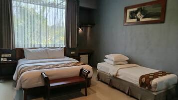 A bedroom with a large bed, a smaller bed, a bench, a nightstand, and a wall-mounted picture.