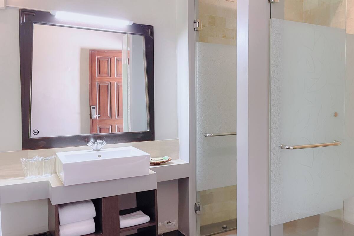 A bathroom with a white sink, a mirror, and a glass shower door.