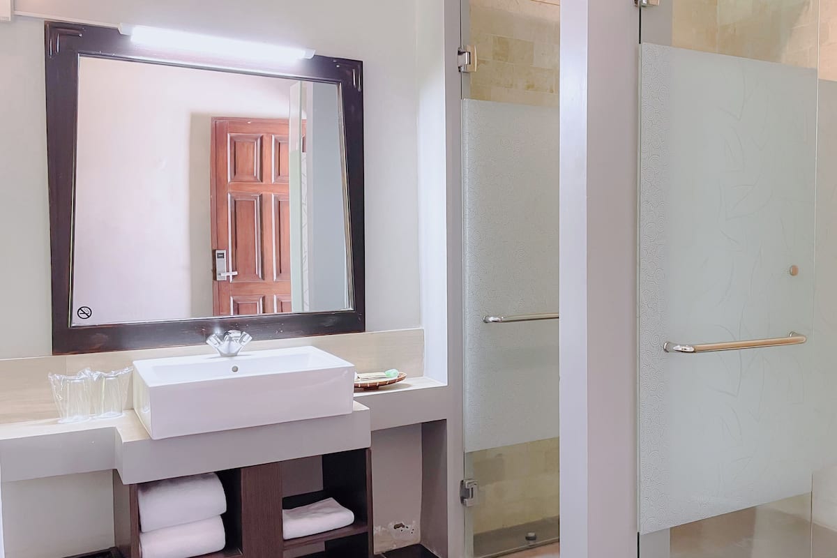 A bathroom with a white sink, a mirror, and a glass shower door.