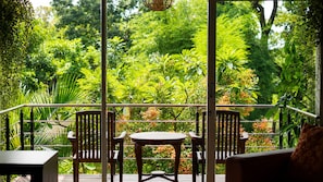 An outdoor seating area with a table and chairs, surrounded by lush greenery and a metal railing. - Bukit Daun Hotel and Resort (Kediri)
