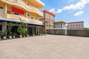 A hotel with a covered outdoor seating area, multiple potted plants, and a clear sky.